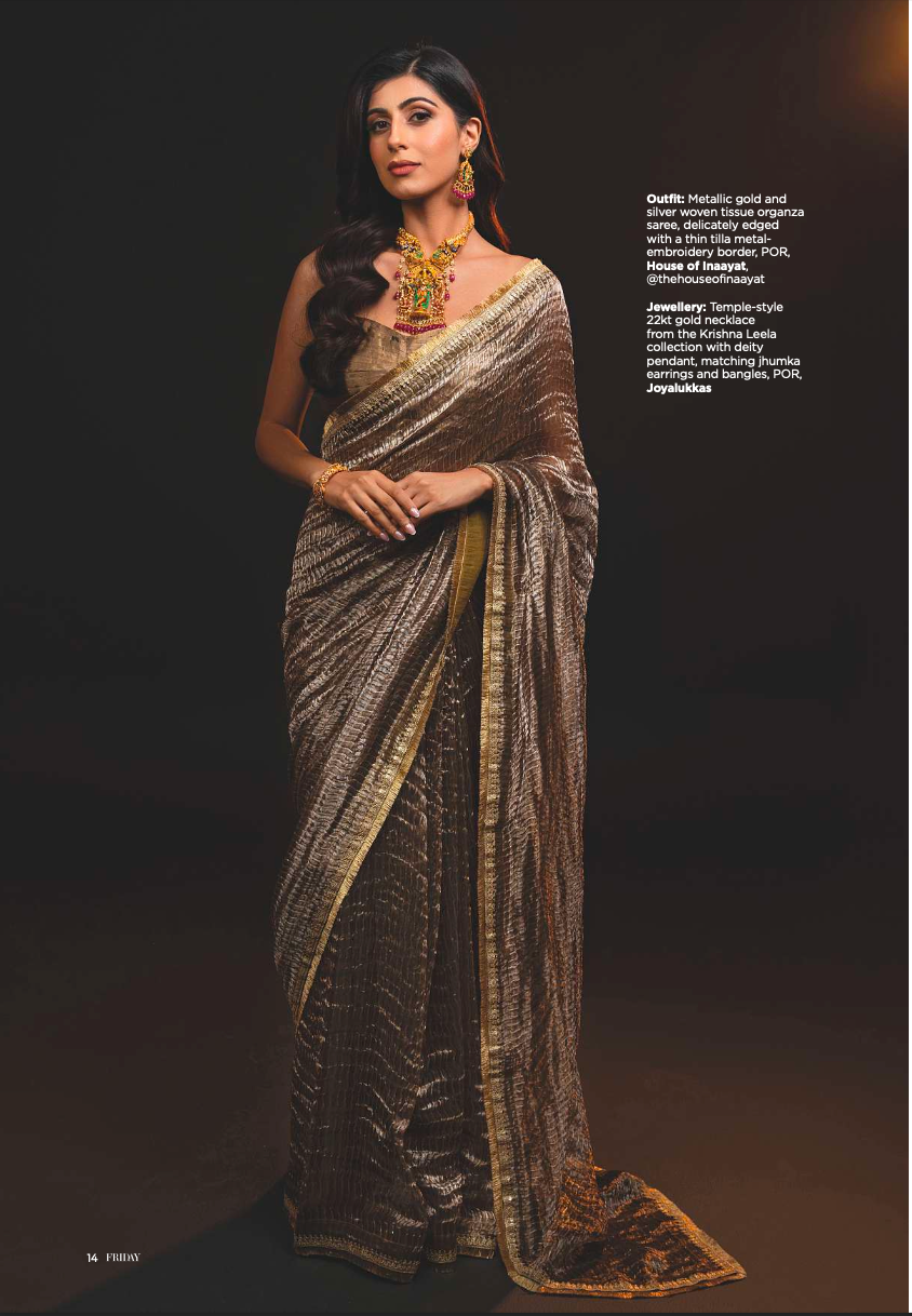 Woman wearing a saree with gold and silver details on a dark background
