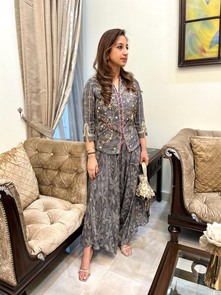 Woman in a patterned outfit standing in a living room with beige furniture and a painting on the wall.
